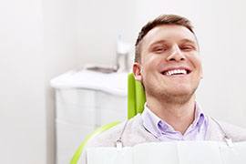Smiling male dental patient, reclining in treatment chair