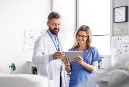 Dental team members standing over electronic tablet, conversing