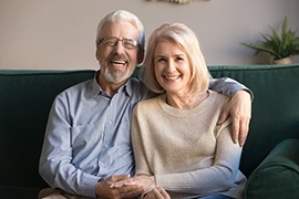 Man and woman on a green couch holding hands and smiling