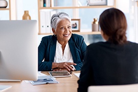 Woman in blue jacket and white shirt interviewing at a work desk
