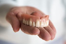 Hand holding upper denture