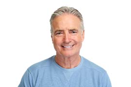 Man with grey hair wearing blue shirt smiling