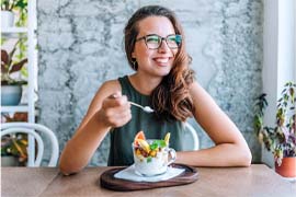 Woman sitting at table smiling eating a healthy snack