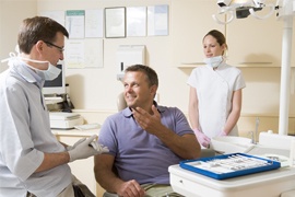 Man in dental chair talking to dentist