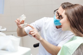 Dentist showing patient an implant supported fixed bridge model