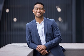 a smiling man resting against a wall