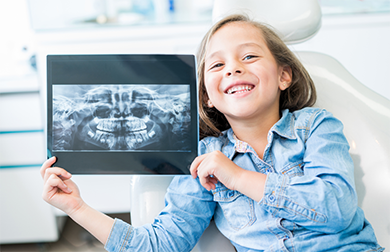 Smiling girl holding her dental x-ray