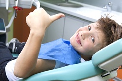 Smiling child in dental chair giving thumbs up