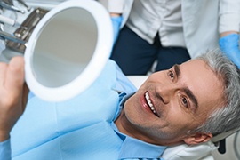 Man smiling at reflection during dental appointment