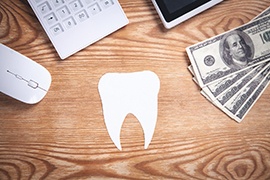 Paper tooth on a table with money nearby