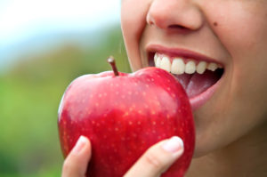Smiling woman eating apple