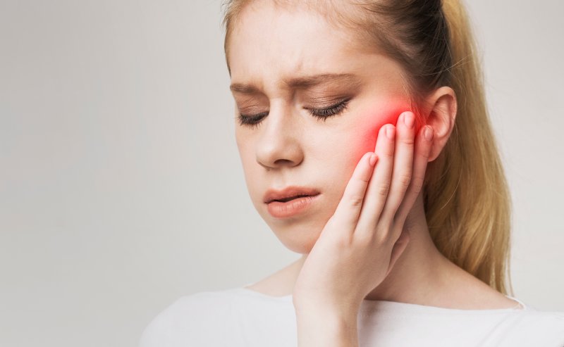 person with tooth sensitivity holding their cheek