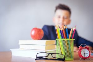 School supplies on desk in front of young boy