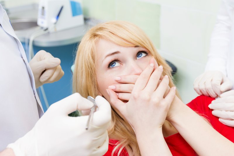 A woman covering her mouth because her dental veneer fell out