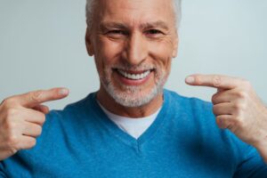 Senior man smiling, showing off dentures.